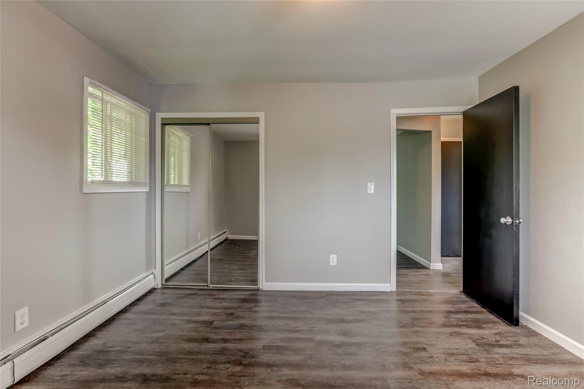 649 West Maple Road, Unit 8 Clawson, MI 48017 - Photo 11 of 16 Spacious interior featuring wood-finish flooring throughout, multiple closets with mirrored sliding doors, and abundant natural light from dual glass doors and transom windows