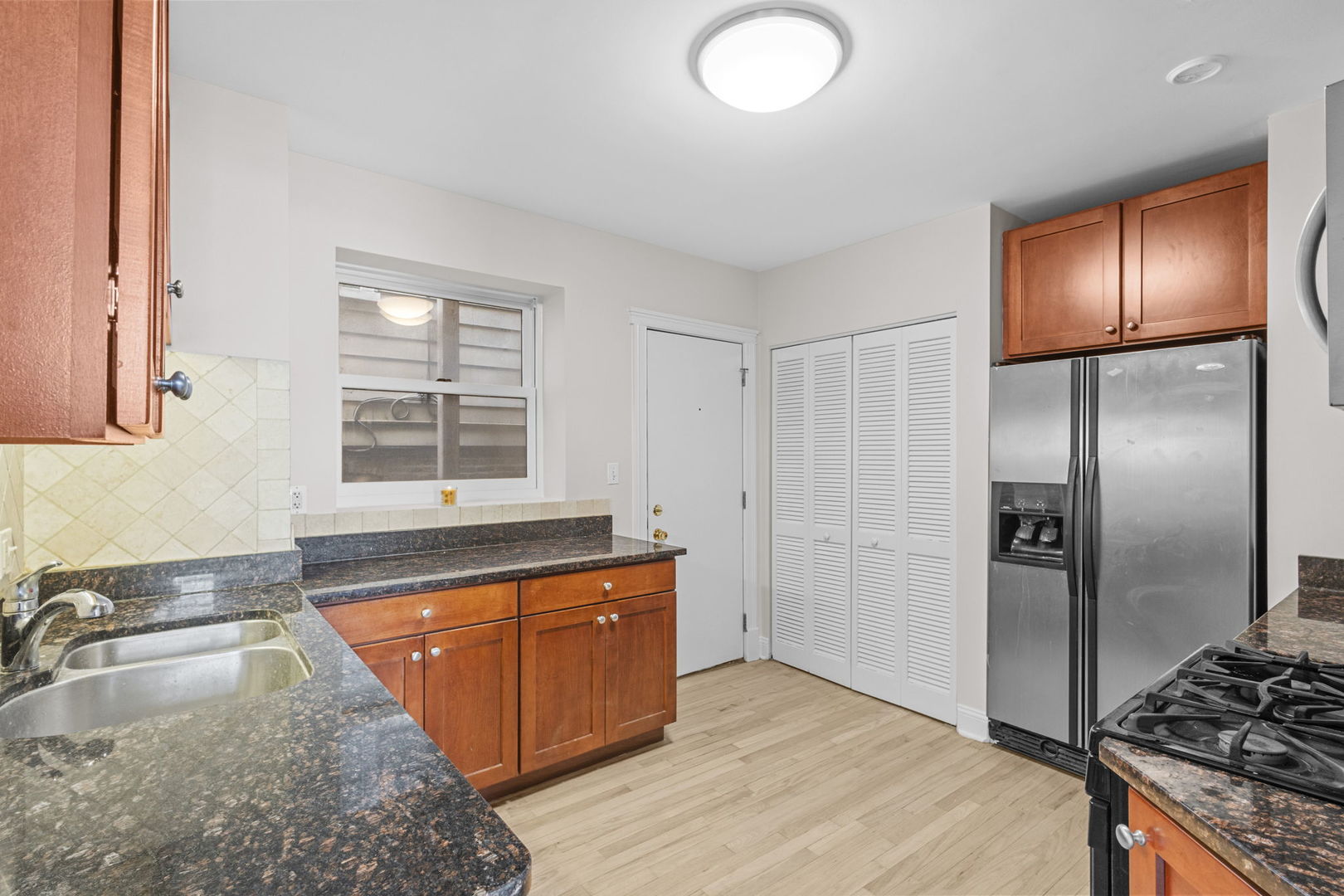 1014 West Roscoe Street, Unit 1F Chicago, IL 60657 - Photo 13 of 15 a kitchen with stainless steel appliances granite countertop a sink stove and refrigerator