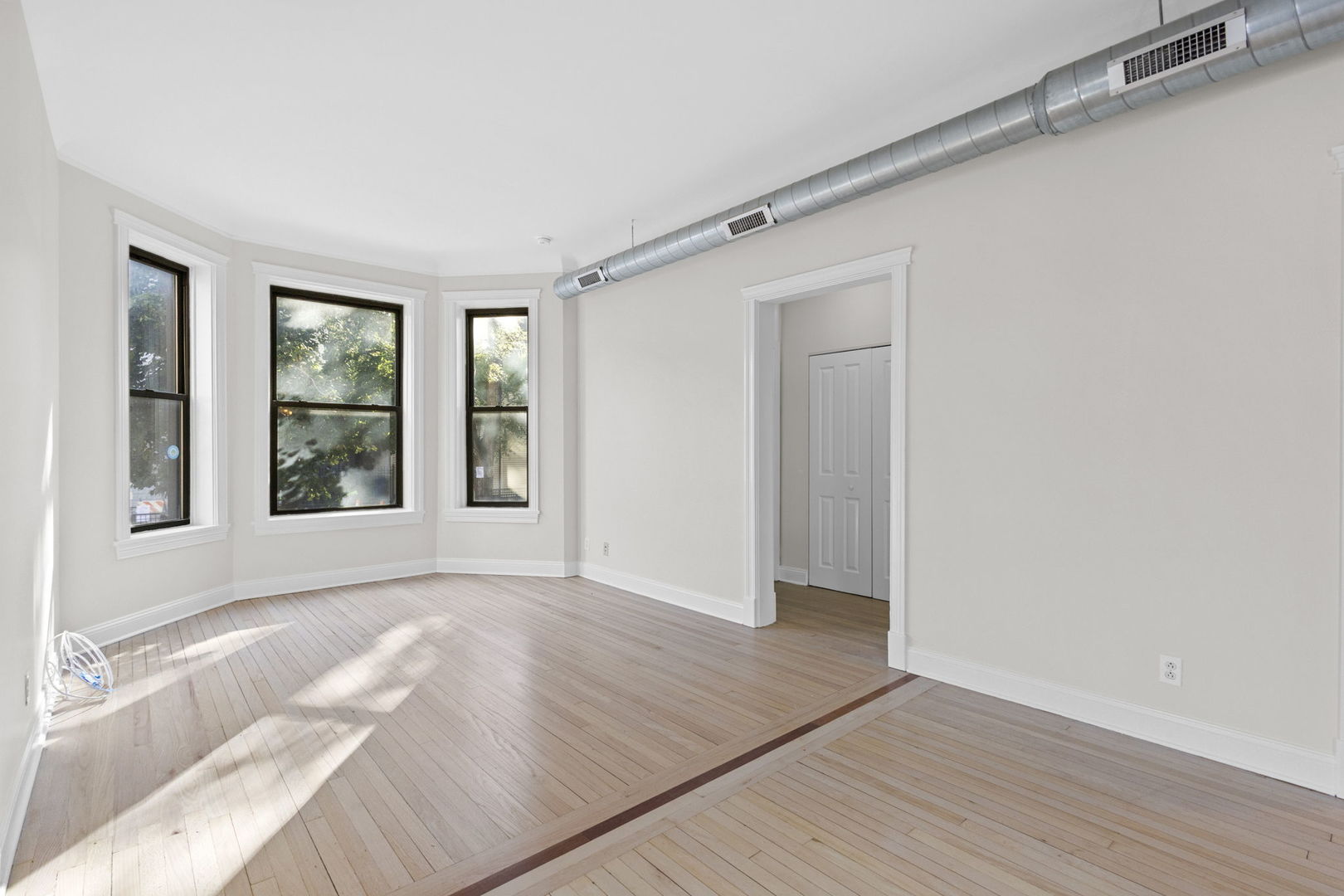 1014 West Roscoe Street, Unit 1F Chicago, IL 60657 - Photo 2 of 15 a view of an empty room with wooden floor and a window