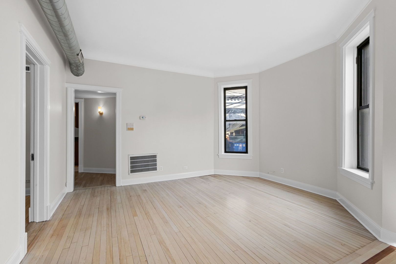 1014 West Roscoe Street, Unit 1F Chicago, IL 60657 - Photo 4 of 15 an empty room with wooden floor and windows