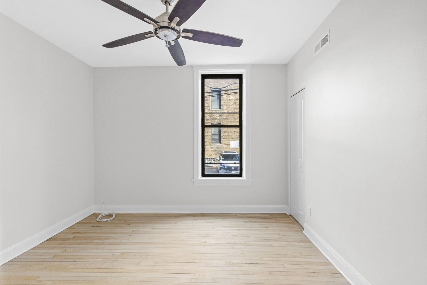 1014 West Roscoe Street, Unit 1F Chicago, IL 60657 - Photo 9 of 15 an empty room with a window and ceiling fan