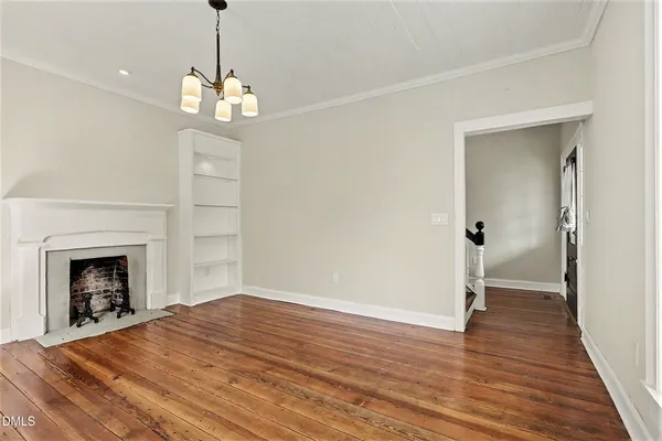 a view of an empty room with wooden floor fireplace and a window
