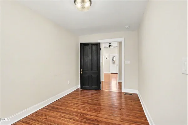 a view of an empty room with wooden floor and closet