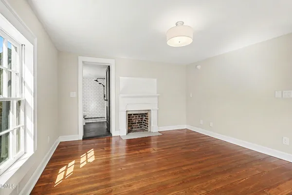 a view of empty room with wooden floor and fireplace