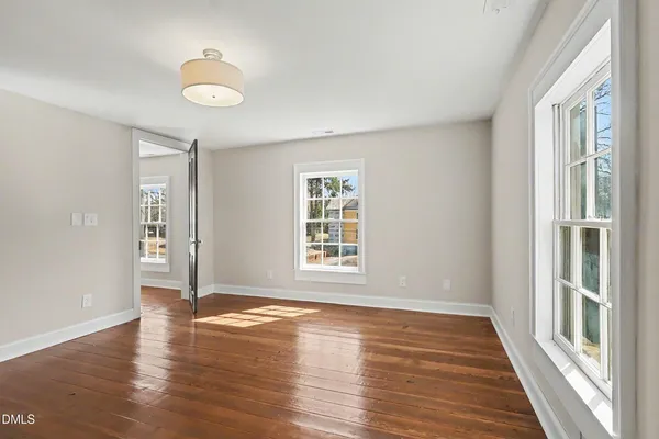 a view of an empty room with wooden floor and a window