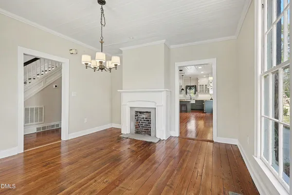a view of a room with wooden floor fireplace and windows