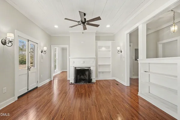 a view of a livingroom with wooden floor a ceiling fan and windows