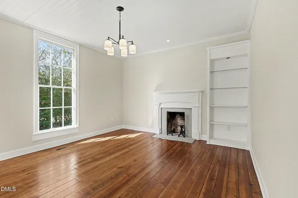 an empty room with wooden floor fireplace and windows