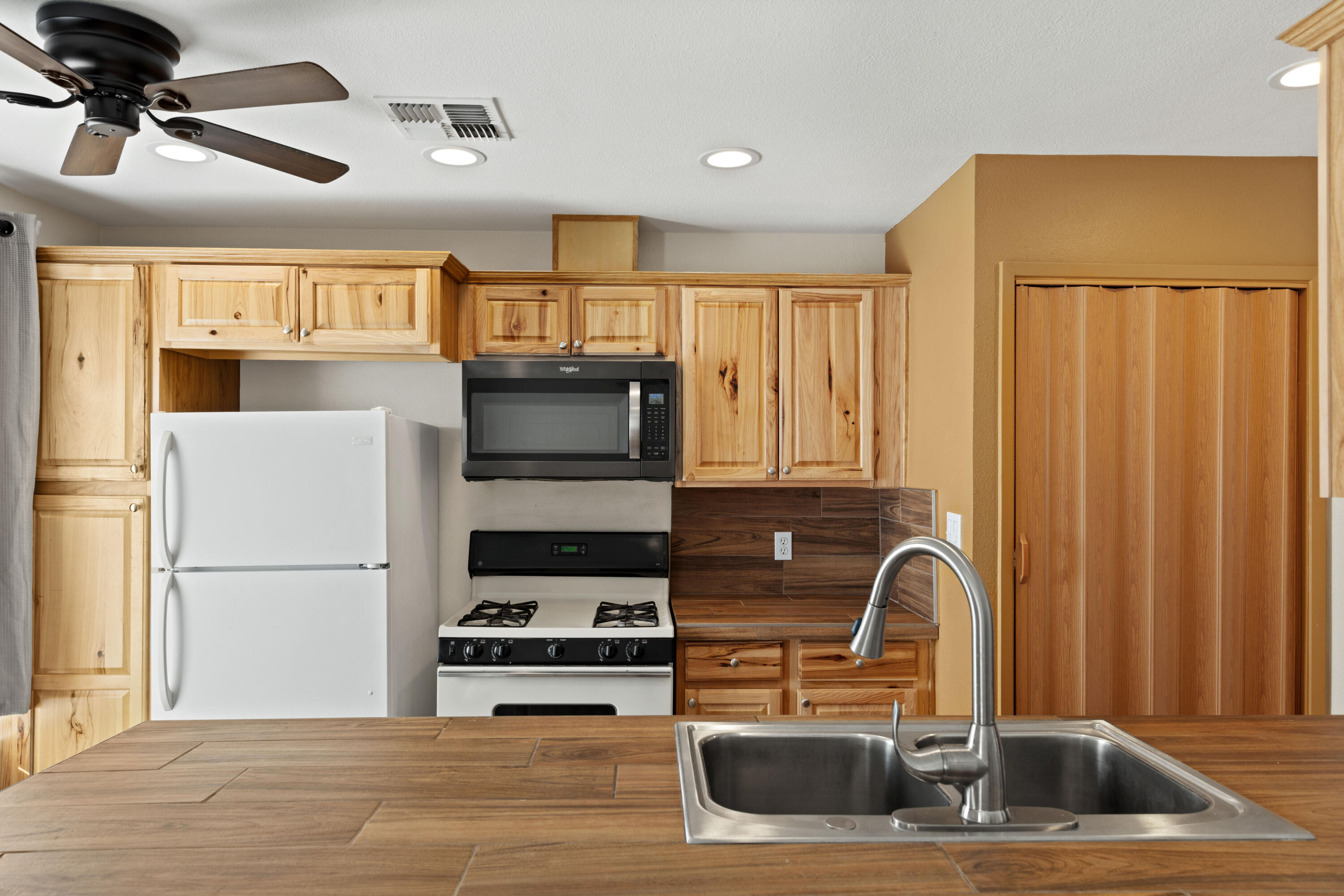 82567 Ave 48, Unit 103 Indio, CA 92201 - Photo 4 of 26 a kitchen with stainless steel appliances granite countertop a refrigerator a stove a sink and a microwave with wooden floor