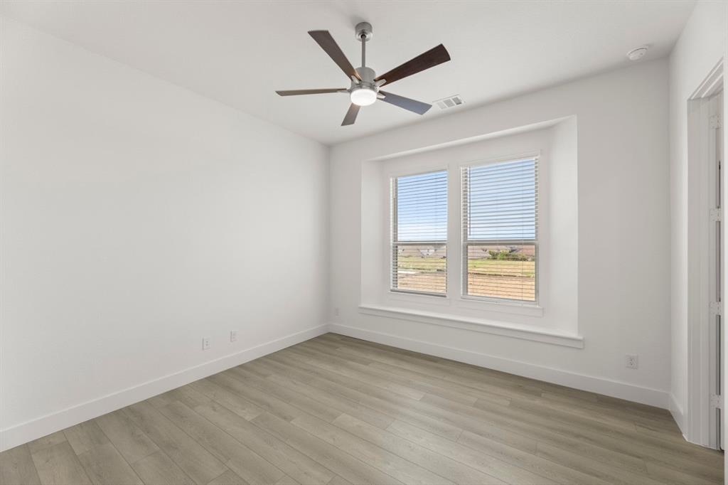 971 Georgetown Place Prosper, TX 75078 - Photo 11 of 34 an empty room with wooden floor fan and windows