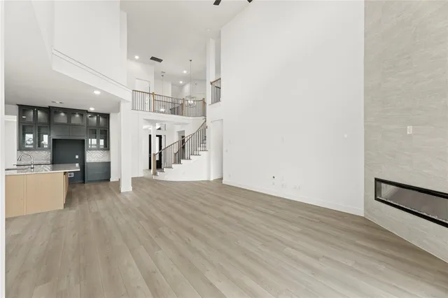 an empty room with wooden floor and a kitchen