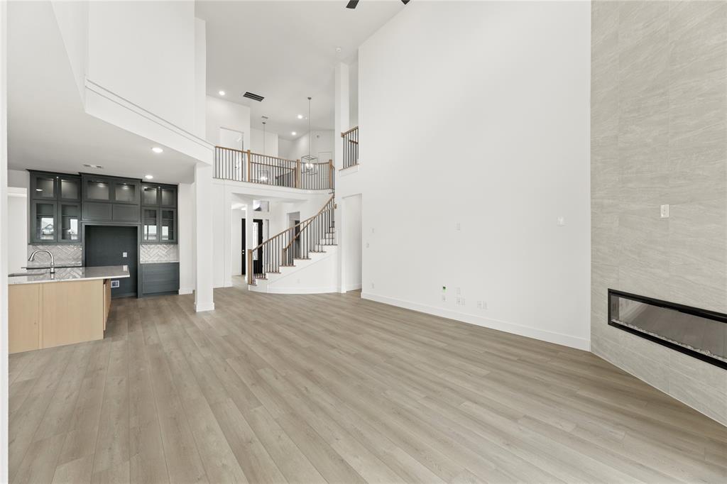 971 Georgetown Place Prosper, TX 75078 - Photo 15 of 34 an empty room with wooden floor and a kitchen