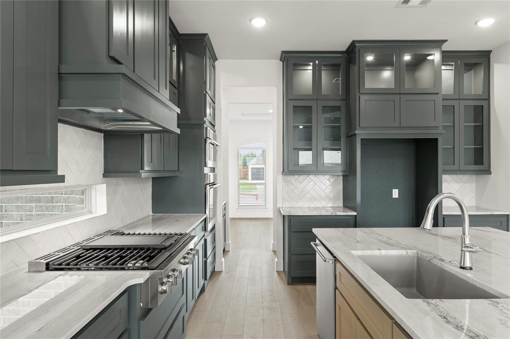 971 Georgetown Place Prosper, TX 75078 - Photo 19 of 34 a kitchen with granite countertop a sink stove and cabinets
