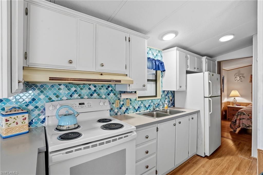 37 Bass Lane Naples, FL 34114 - Photo 2 of 29 Kitchen with white appliances, light countertops, light wood-style floors, white cabinetry, and under cabinet range hood