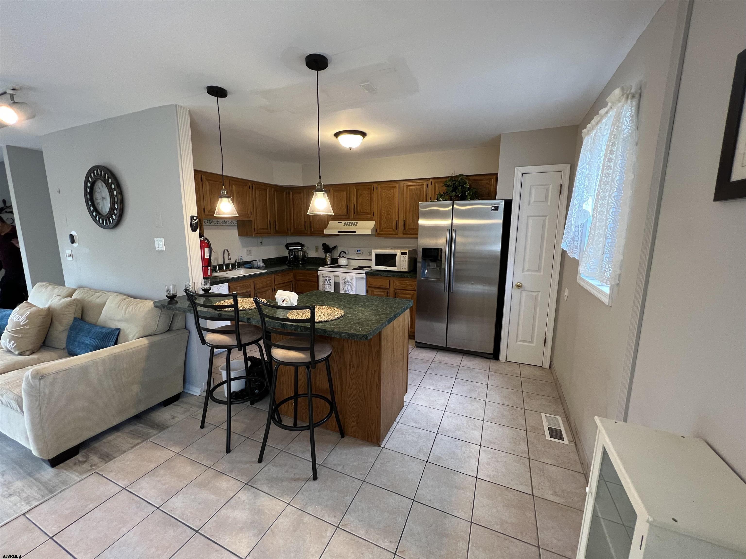 11 Surfside Road, Unit 11 Brigantine, NJ 08203 - Photo 18 of 21 a kitchen with granite countertop a refrigerator a sink a dining table and chairs