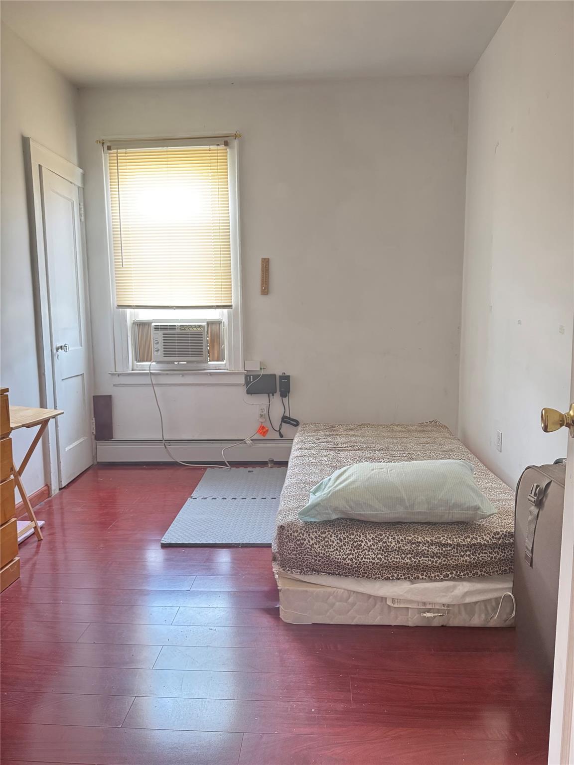 88-16 85th Street Queens, NY 11421 - Photo 4 of 11 Bedroom featuring hardwood / wood-style floors, baseboard heating, and cooling unit