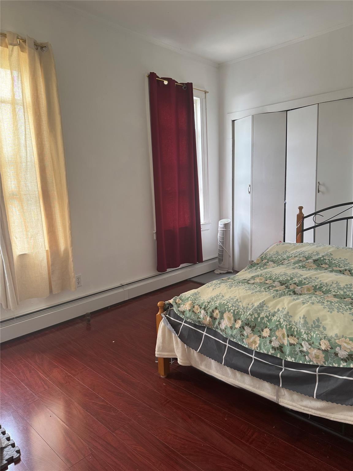 88-16 85th Street Queens, NY 11421 - Photo 5 of 11 Bedroom featuring a baseboard heating unit, a closet, wood finished floors, and ornamental molding
