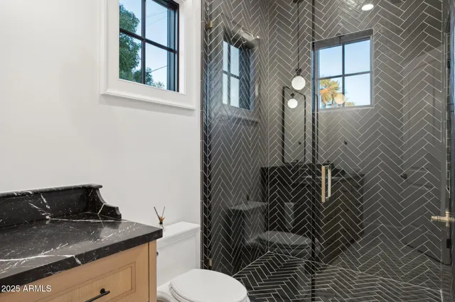 a bathroom with a granite countertop sink and a toilet