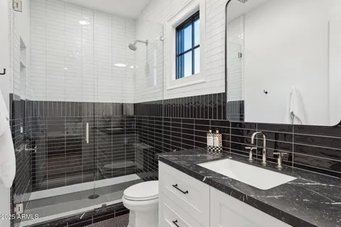 a bathroom with a granite countertop toilet sink and mirror