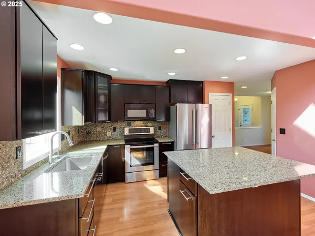 a kitchen with stainless steel appliances granite countertop a sink stove and refrigerator