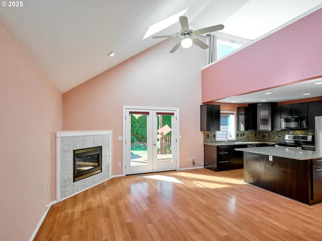 a kitchen with stainless steel appliances granite countertop a stove top oven a sink dishwasher a dining table and chairs with wooden floor