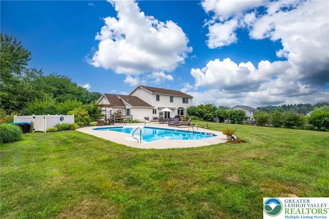 a view of a house with pool and a yard