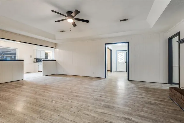 a view of empty room with wooden floor and kitchen view