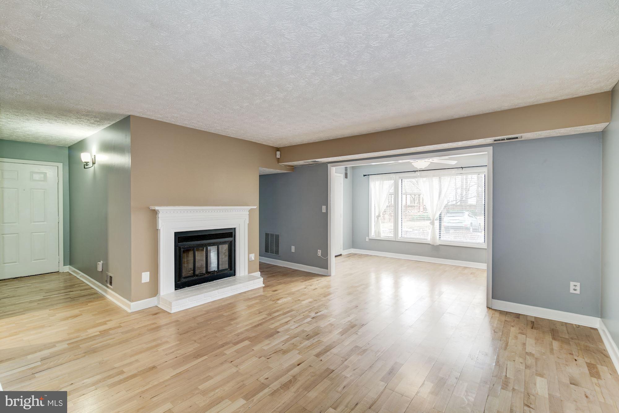 2224 Hunter's Run Drive, Unit 2224 Reston, VA 20191 - Photo 2 of 21 a view of an empty room with wooden floor fireplace and a window