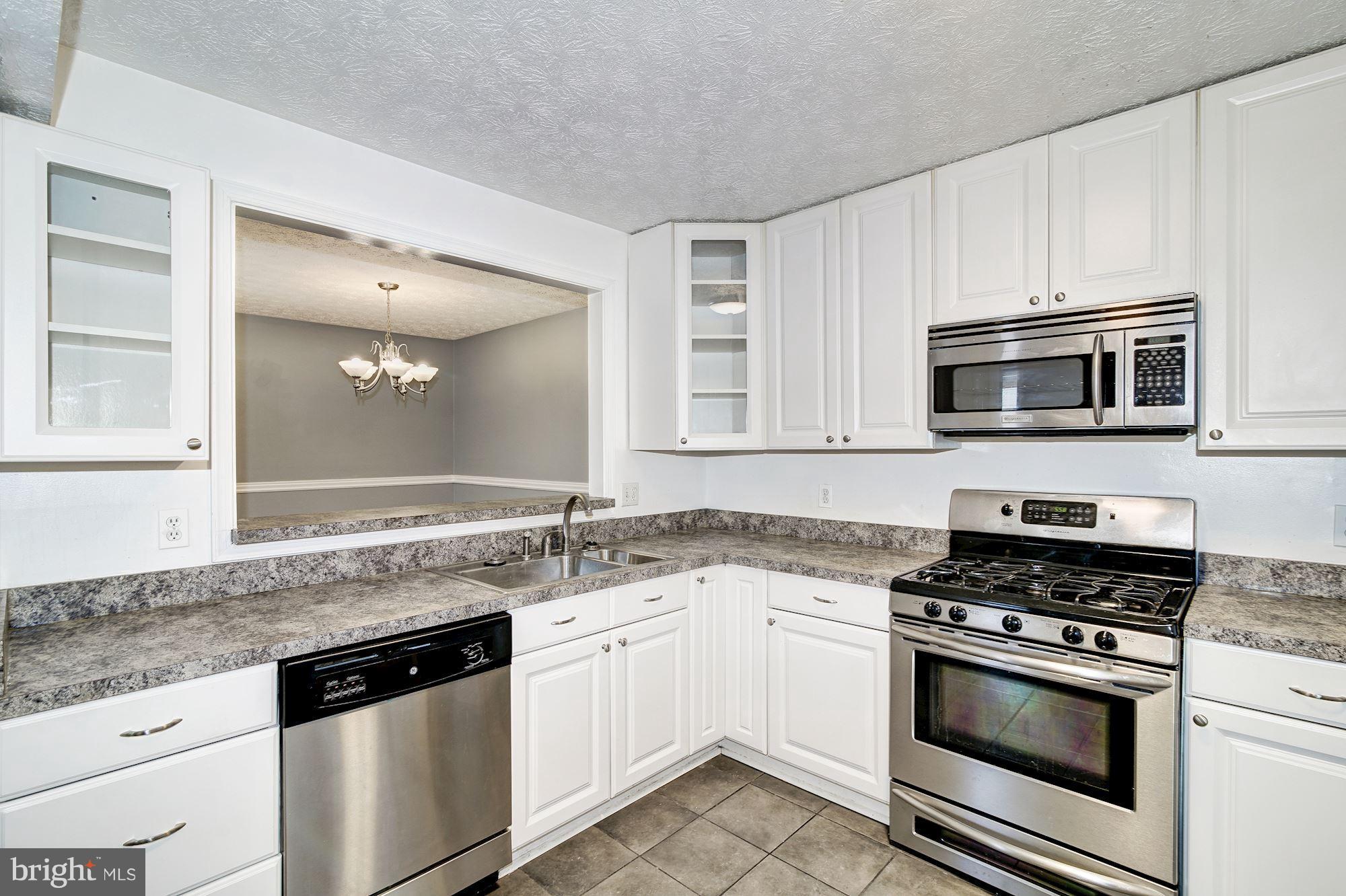 2224 Hunter's Run Drive, Unit 2224 Reston, VA 20191 - Photo 11 of 21 a kitchen with granite countertop a sink stove and microwave