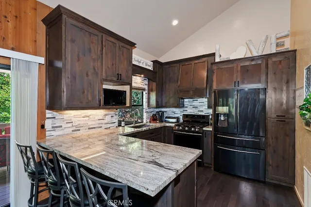 a kitchen with granite countertop a refrigerator and a stove top oven