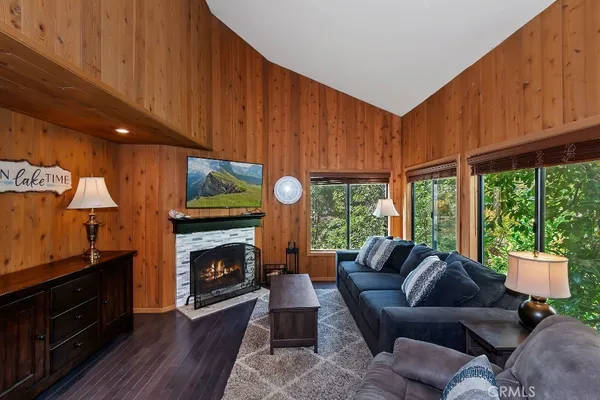 a living room with furniture a fireplace a flat screen tv and windows