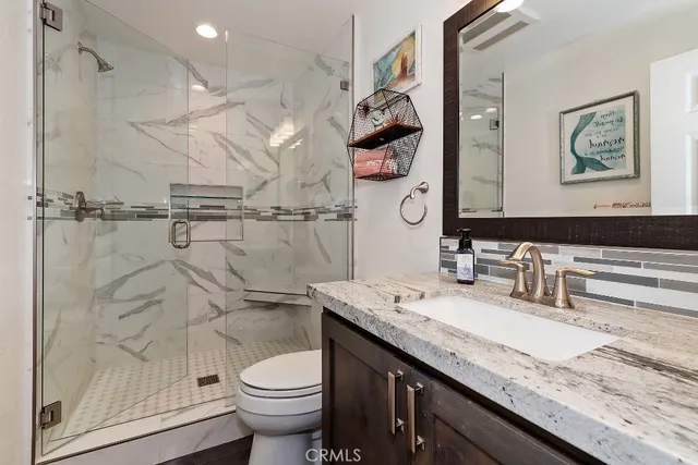 a bathroom with a granite countertop sink a toilet and a mirror