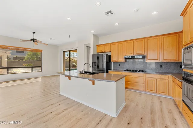 a large kitchen with stainless steel appliances a refrigerator a sink and a stove top oven