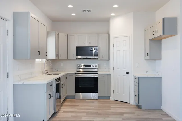 a kitchen with stainless steel appliances granite countertop a stove a sink and a microwave