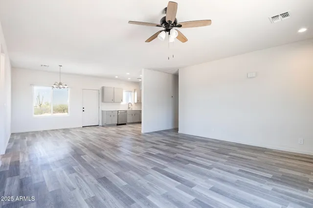 a view of an empty room with a kitchen and wooden floor