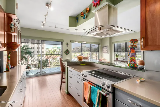 a kitchen with stainless steel appliances granite countertop a stove and a view of living room