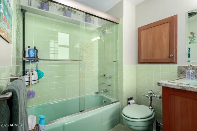 a bathroom with a granite countertop bathtub shower sink vanity and toilet