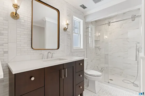 a bathroom with a double vanity sink toilet mirror and shower