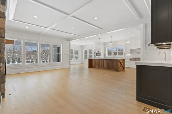 a view of a kitchen with kitchen island a sink wooden floor and a large window