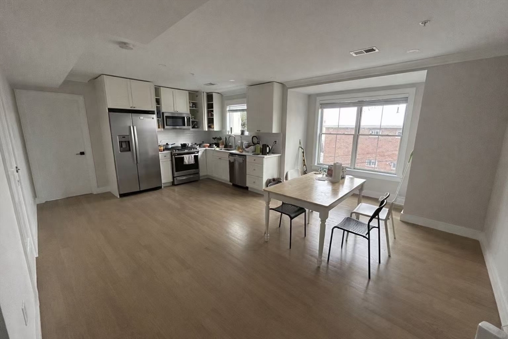 a kitchen with stainless steel appliances a dining table chairs and refrigerator