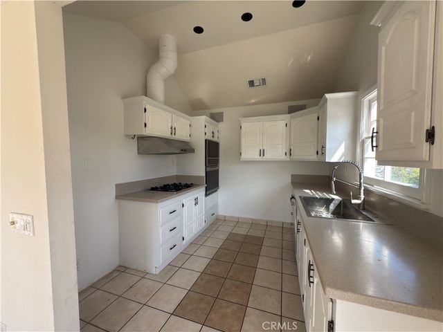 a kitchen with granite countertop a sink a stove and white cabinets