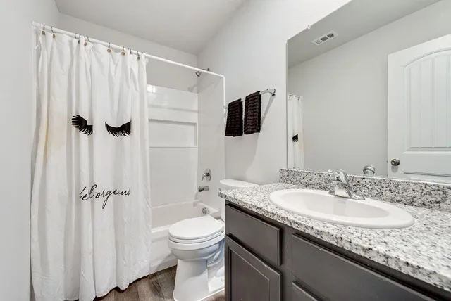 a bathroom with a granite countertop sink a mirror and a toilet