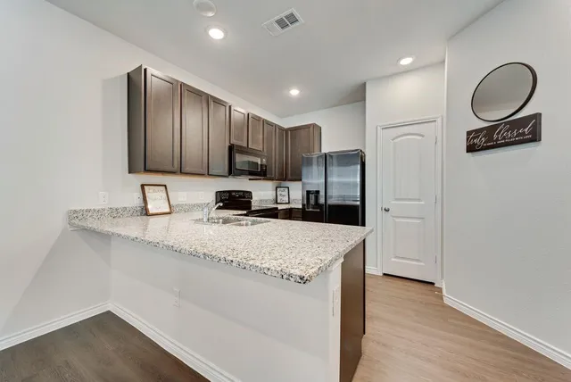 a kitchen with kitchen island granite countertop a sink refrigerator and cabinets