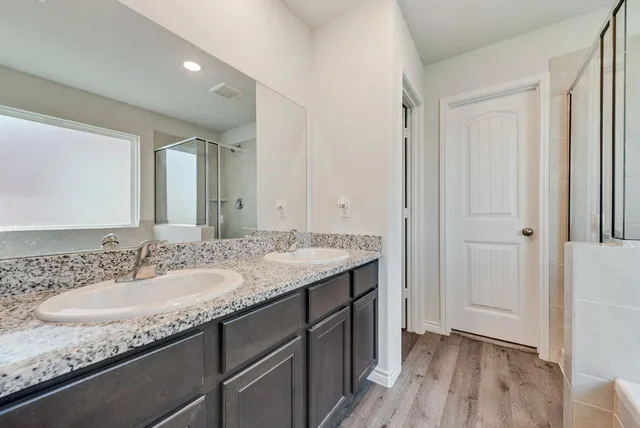 a bathroom with a granite countertop sink a mirror and a shower