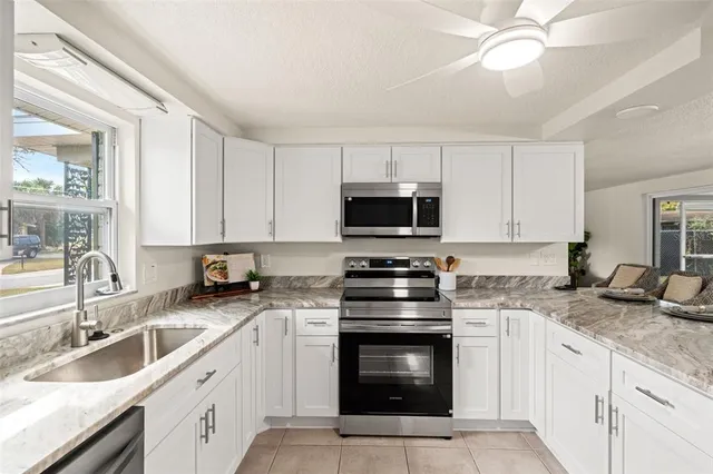 a kitchen with granite countertop a sink cabinets and stainless steel appliances