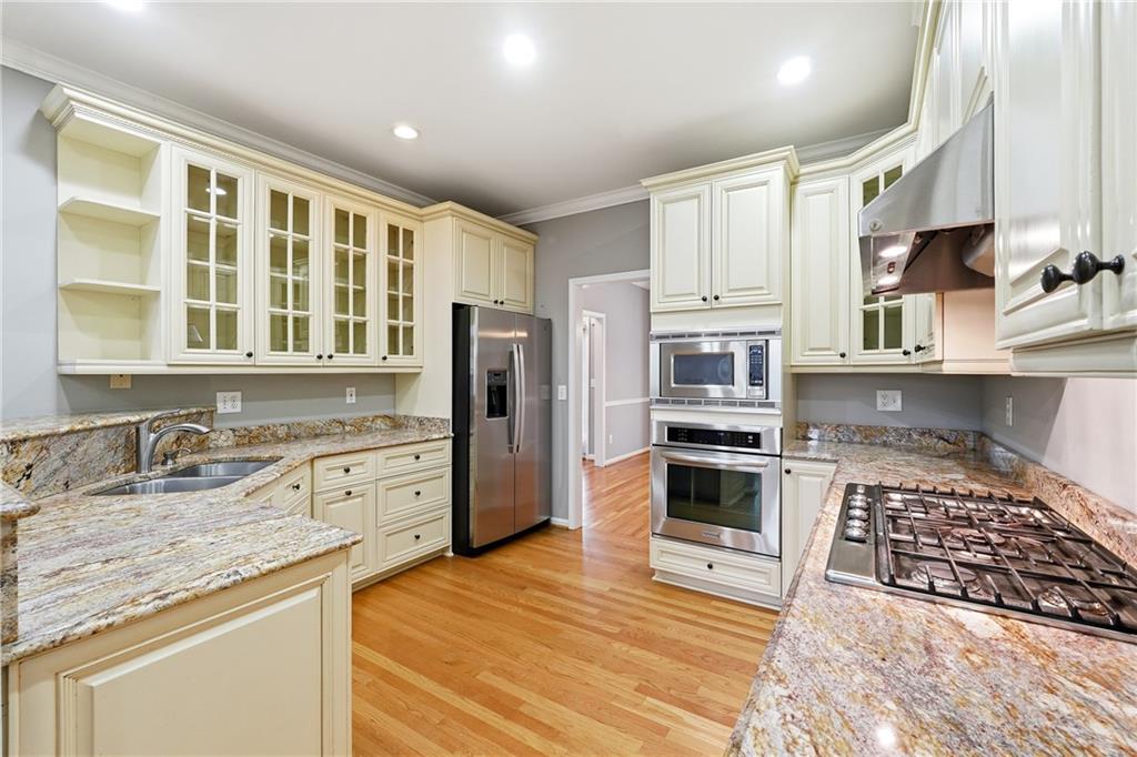5145 Harbour Ridge Drive Alpharetta, GA 30005 - Photo 7 of 25 a kitchen with stainless steel appliances granite countertop a stove top oven a sink dishwasher a refrigerator and cabinets with wooden floor
