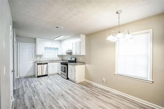 a kitchen with kitchen island white cabinets a sink dishwasher and a stove with wooden floor
