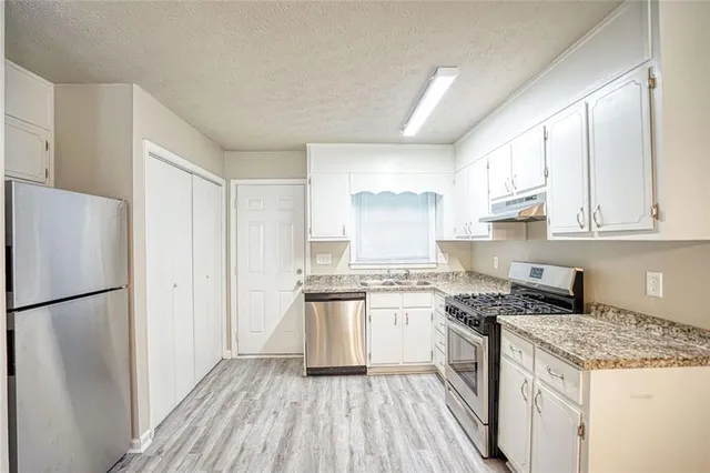 a kitchen with a sink a refrigerator a stove and white cabinets