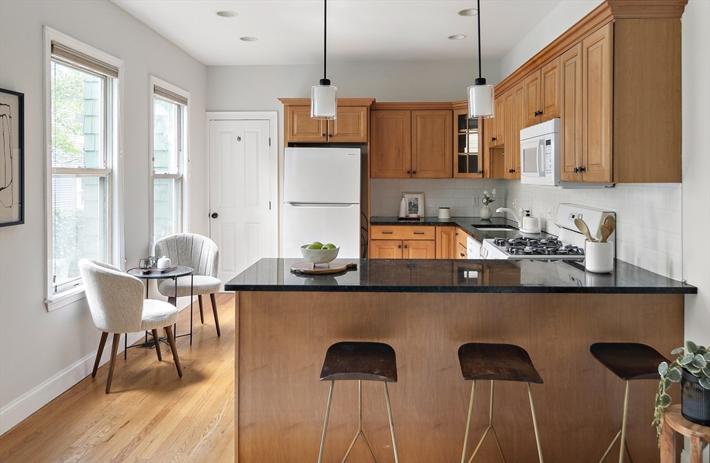 28 Summer Street, Unit 1 Somerville, MA 02143 - Photo 5 of 14 a kitchen with stainless steel appliances kitchen island granite countertop a sink and cabinets