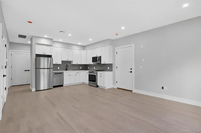 a large white kitchen with a refrigerator a stove top oven and white cabinets